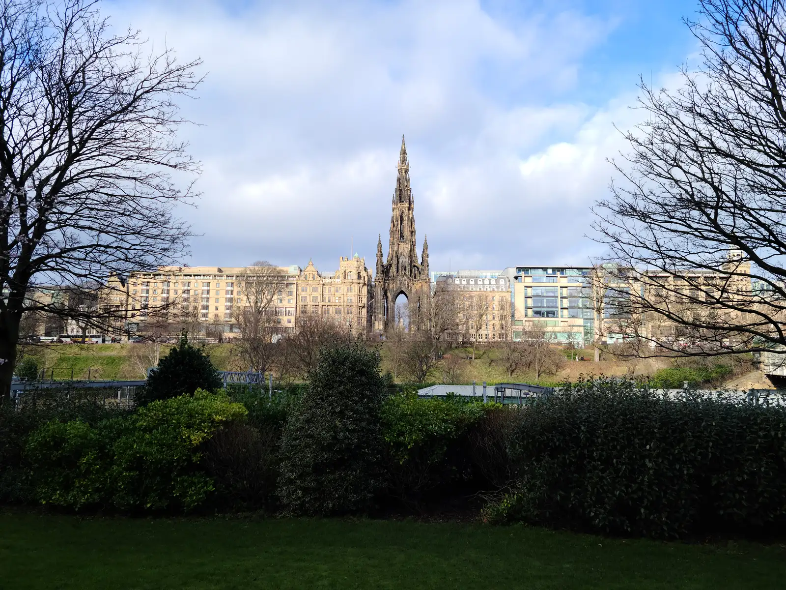 Scott Monument's gothic spire rising above Princes Street buildings seen from East Princes Street Gardens through bare winter trees